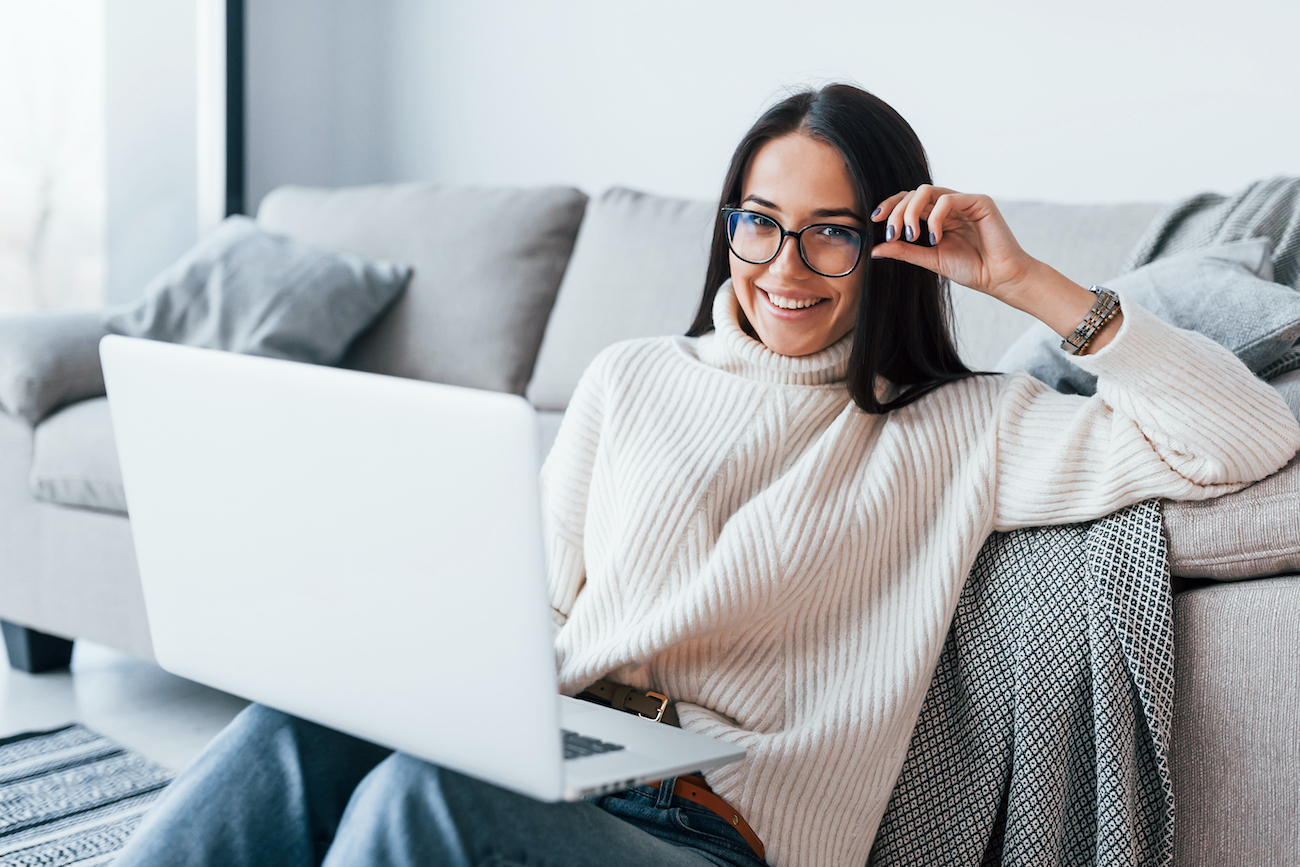 Young beautiful woman in glasses sitting at home alone with laptop