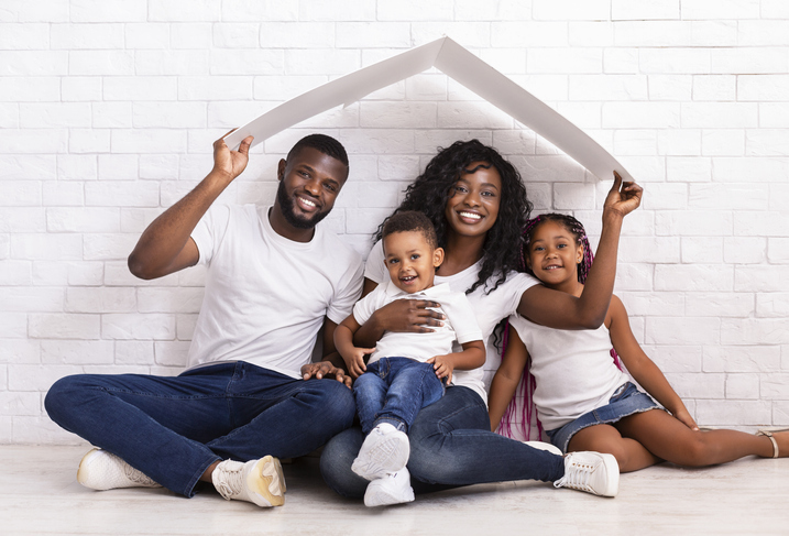 Beautiful Black Family Holding Cardboard Roof Dreaming Of New Home